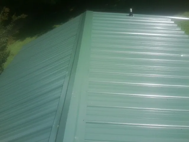 New green metal panels meeting at the ridge of a roof — Flat Roof Repair work by our crew in Bruin