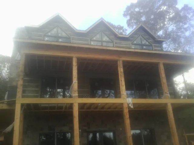 Dormers and porch framing on a large log home under construction — Roof Coating work by our crew in Bruin