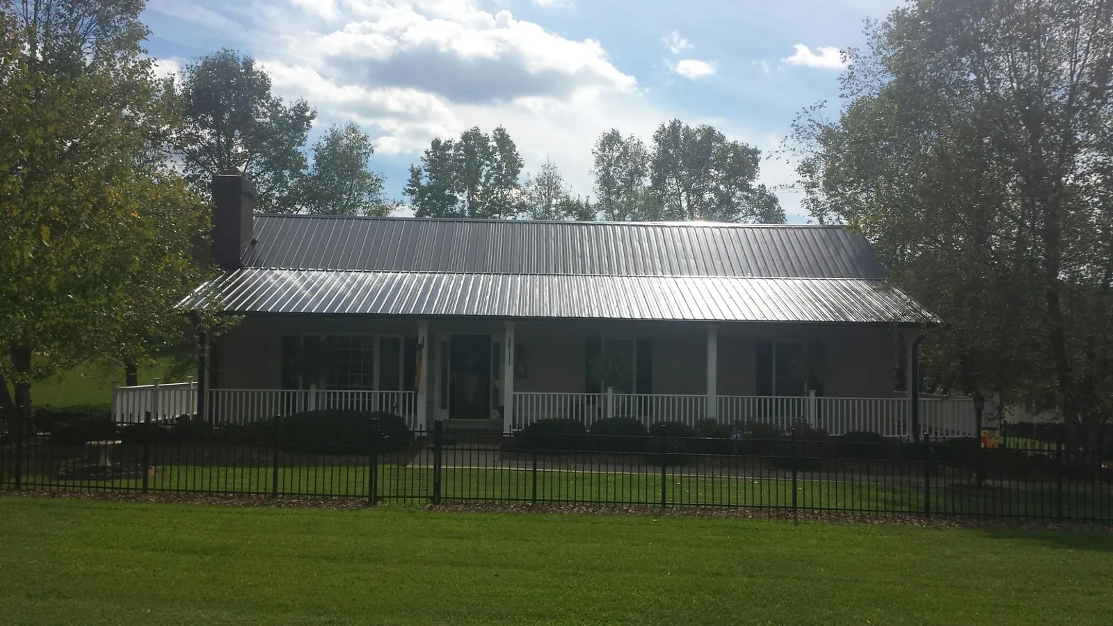 Gray metal roof on a brick ranch with a full width front porch — Gutter Guard Installation work by our crew in Bruin
