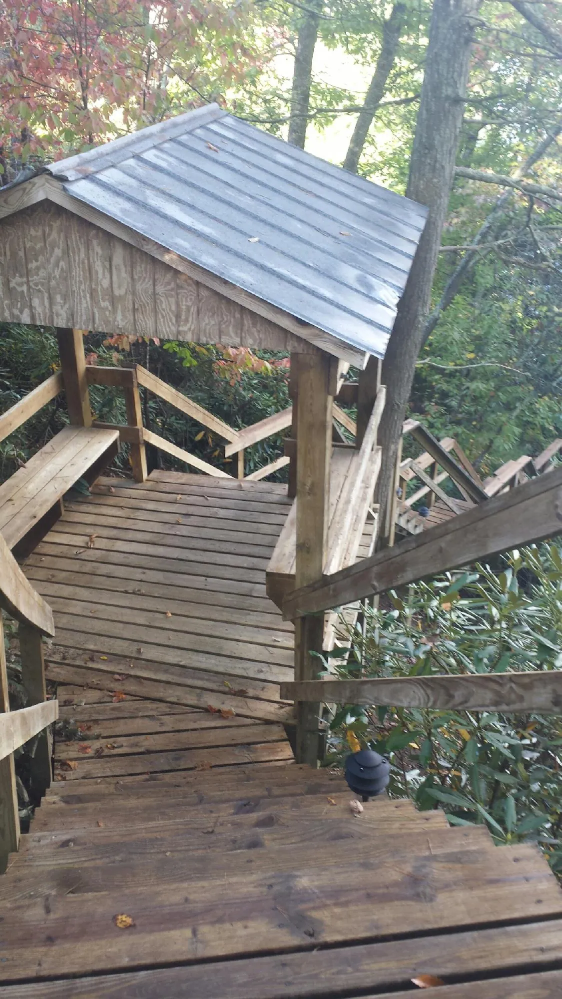 Metal roofed shelter over wooden steps on a wooded walkway — Skylight Repair & Installation work by our crew in Bruin