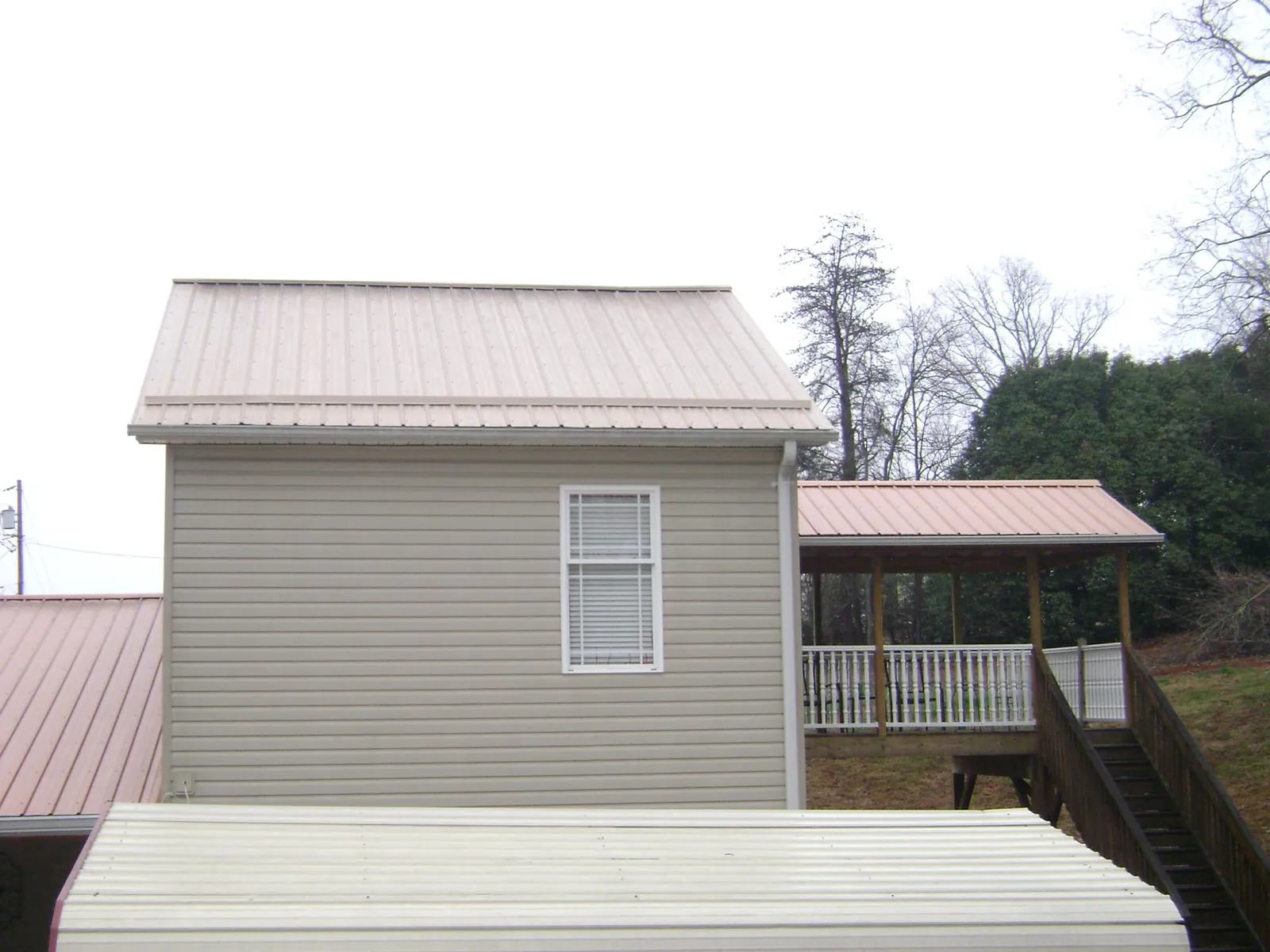 Tan metal roofs on a two story addition and attached porch, from a Roof Replacement job in Bruin