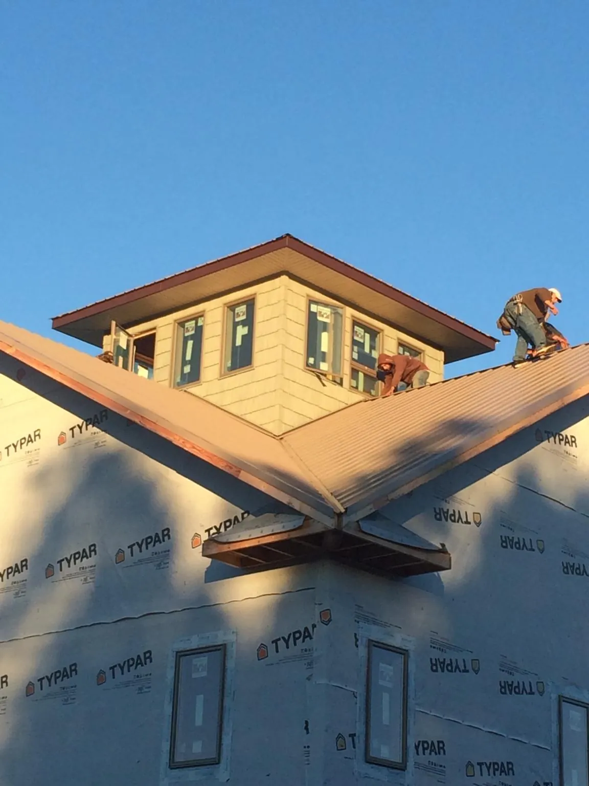 Roofers working around a rooftop cupola on a new metal roof at sunset — Roof Waterproofing in Bruin by Roofing Brothers